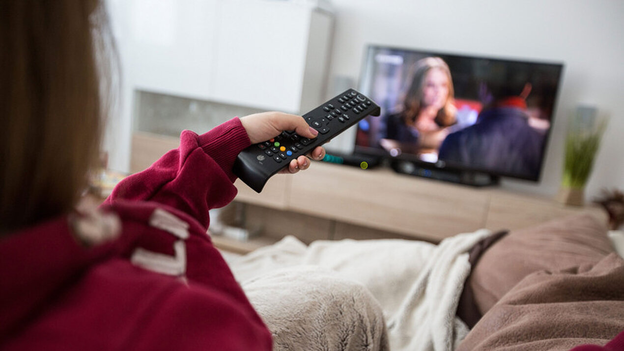 Frau beim Fernsehen mit Fernbedienung